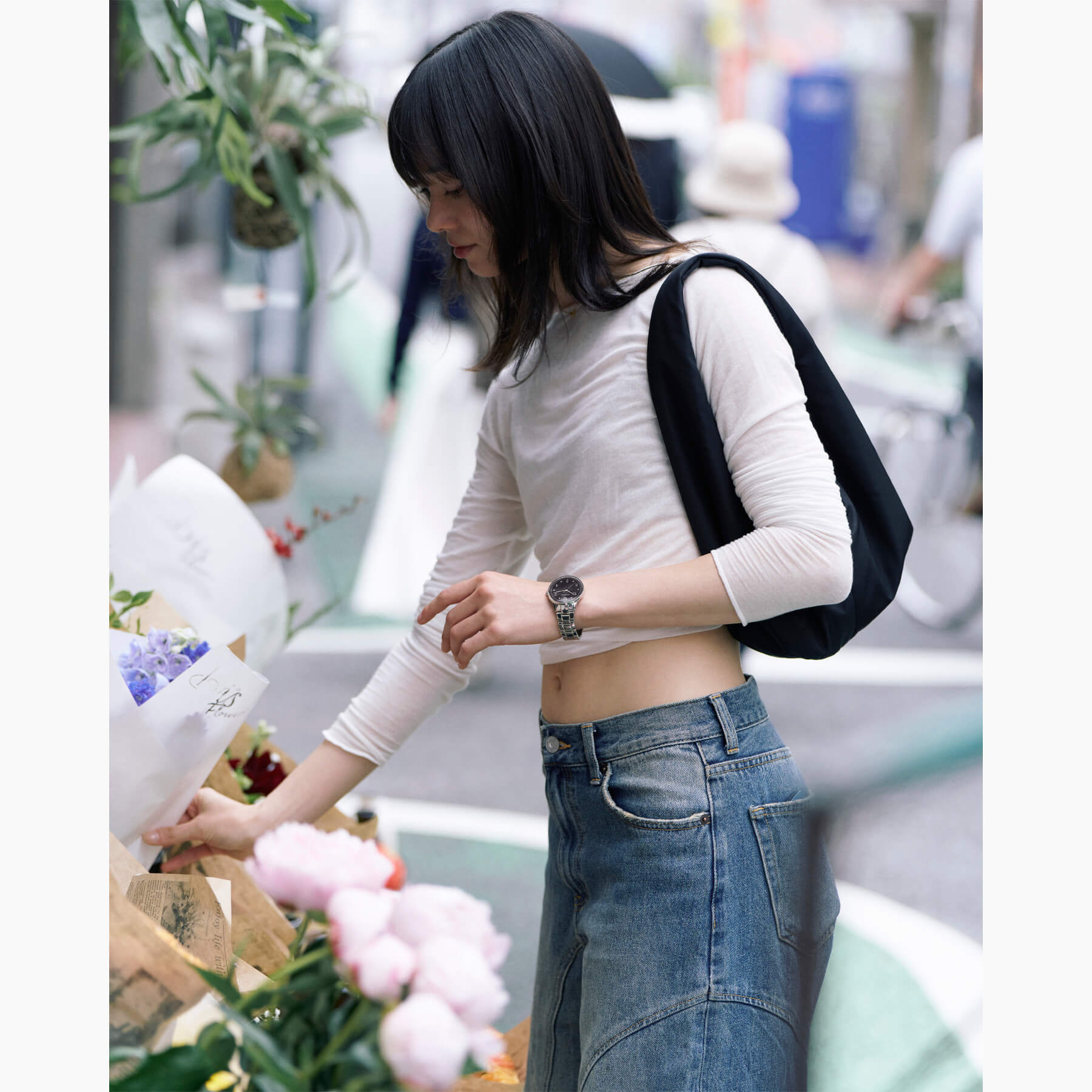 ヴェアホイ Petite Royal Blackを着用した女性、花屋でブーケを選ぶシーン。黒い木目ダイヤルとシルバーブレスが自然光に映える北欧デザインウォッチ