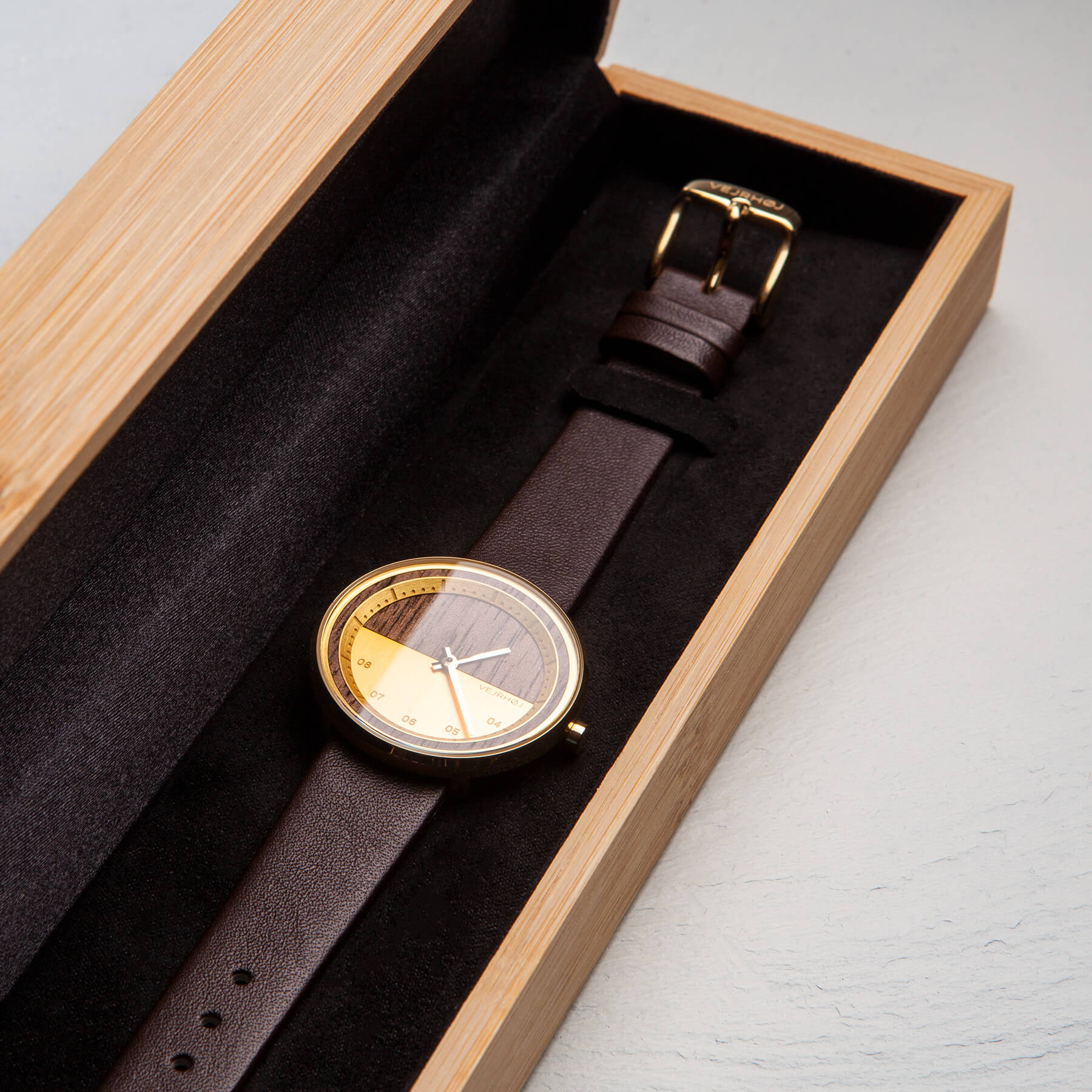 竹箱の中にゴールドと茶色の腕時計が置かれている