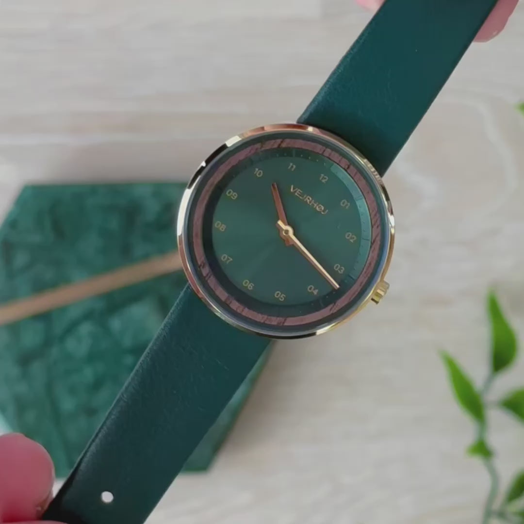 グリーン仕上げの文字盤がゴールド色のケースに包まれている腕時計 VEJRHØJ