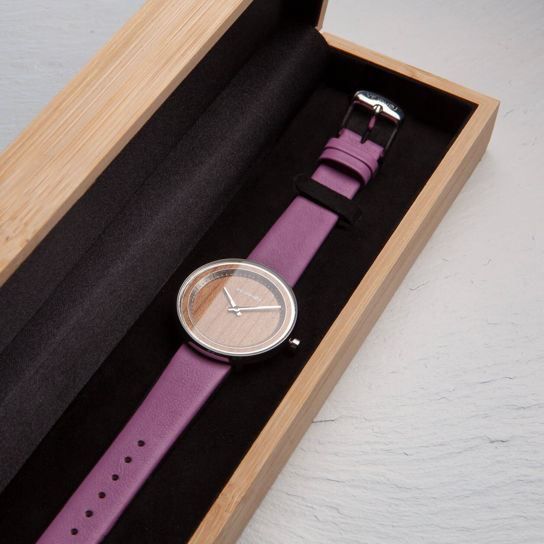 紫色のベルトのレディーズ時計が木箱の中に。ウェアホイ腕時計